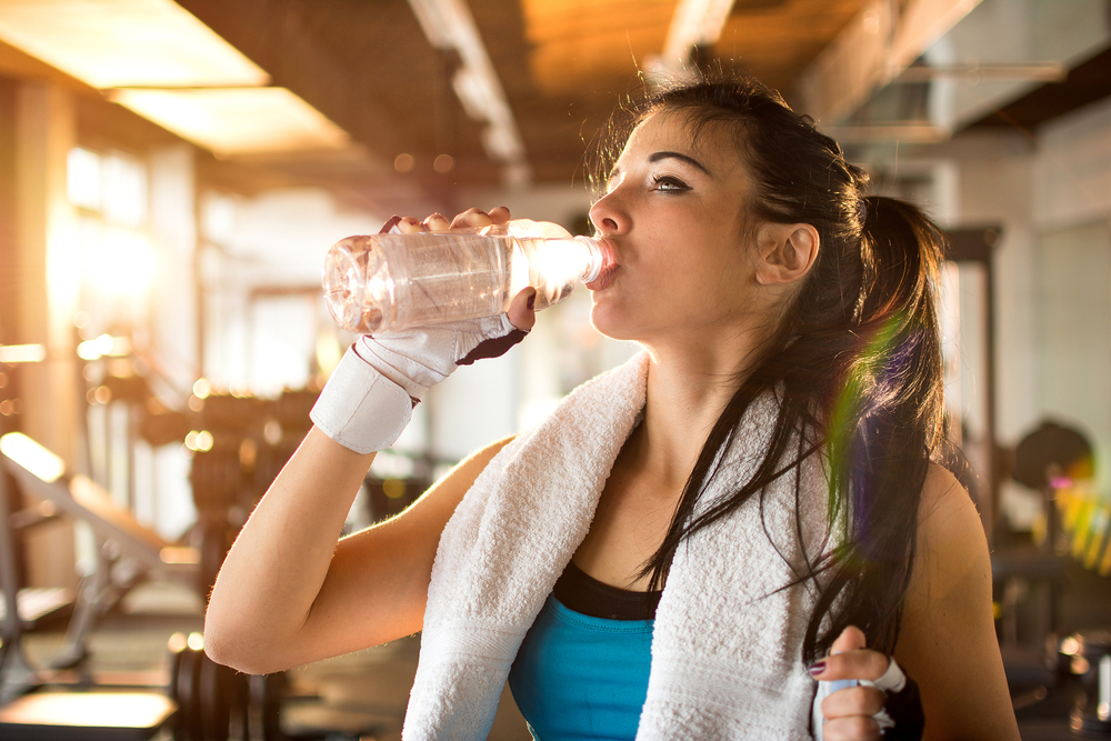 woman drinking water after strength training