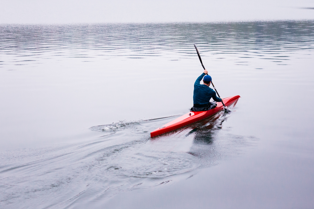 male kayaking in bay alone
